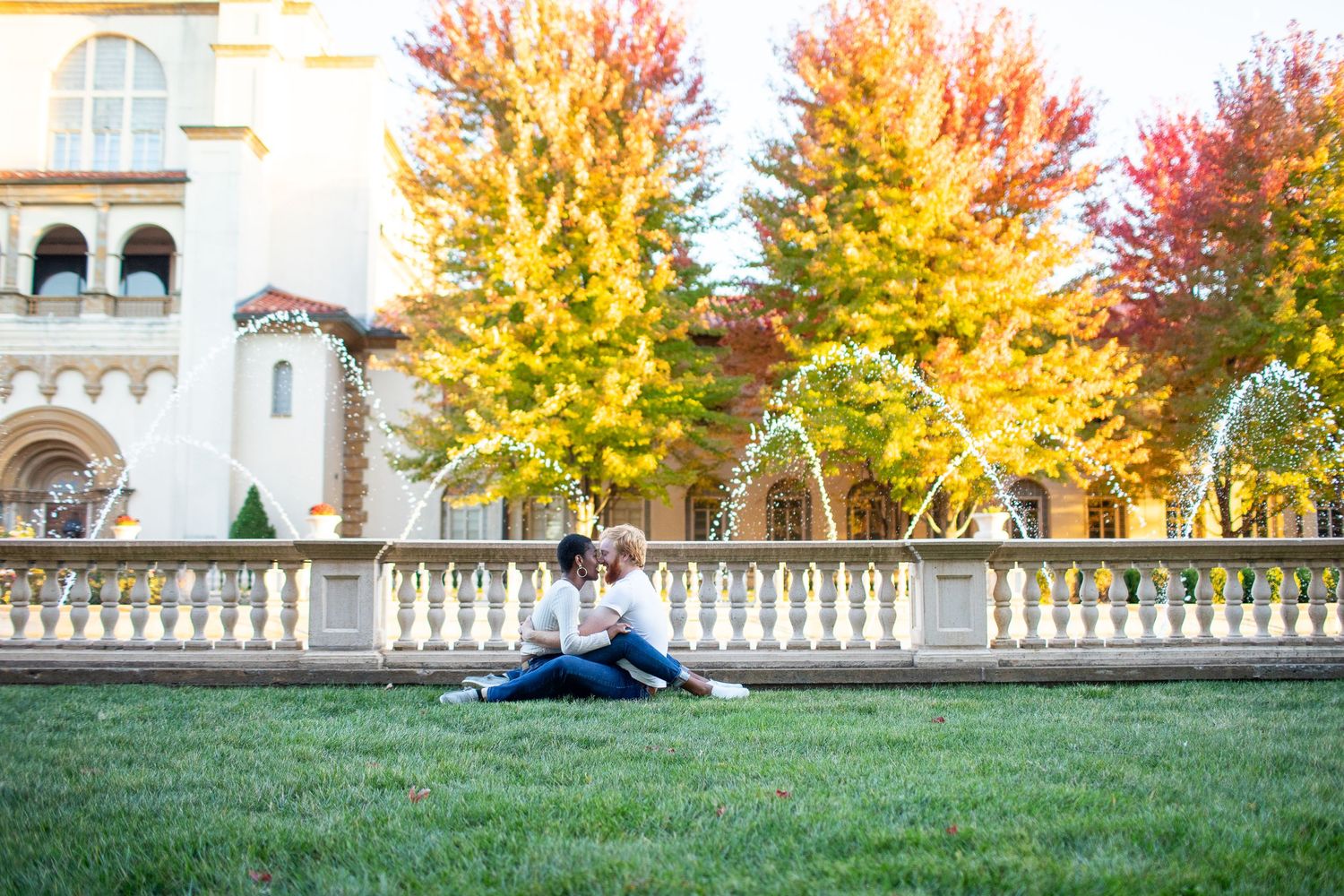 Person doing splits on historic balustrade with autumn trees in background.