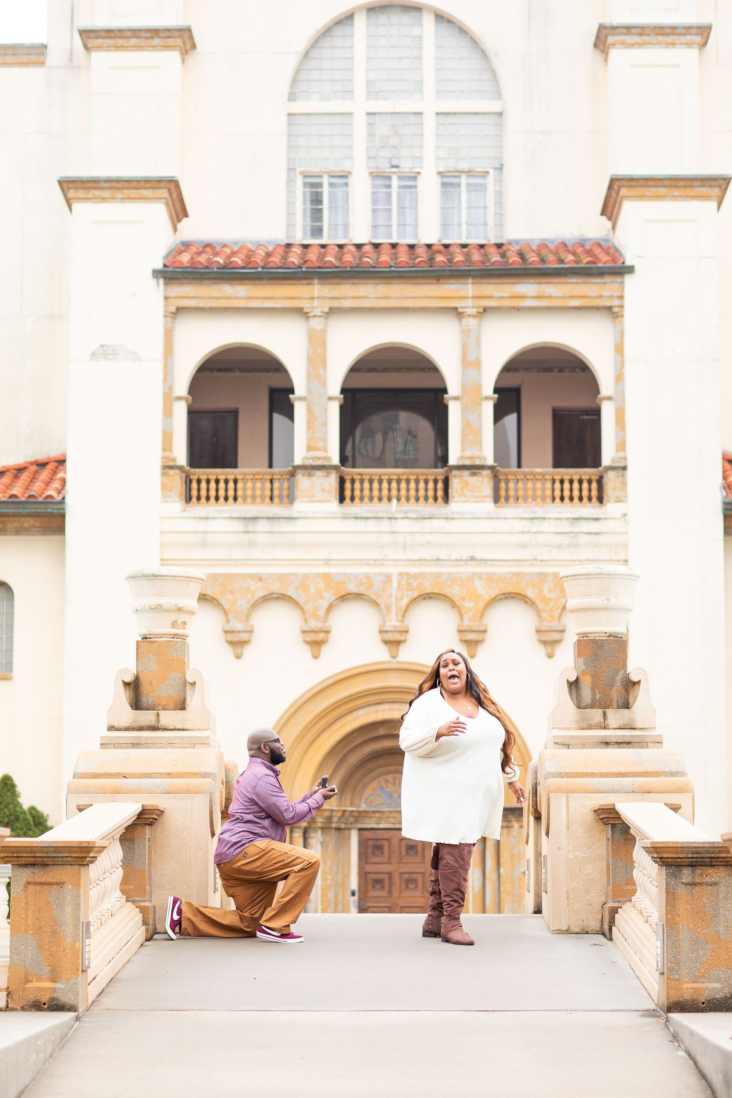 A proposal moment on steps of Mediterranean-style building with arched architecture.