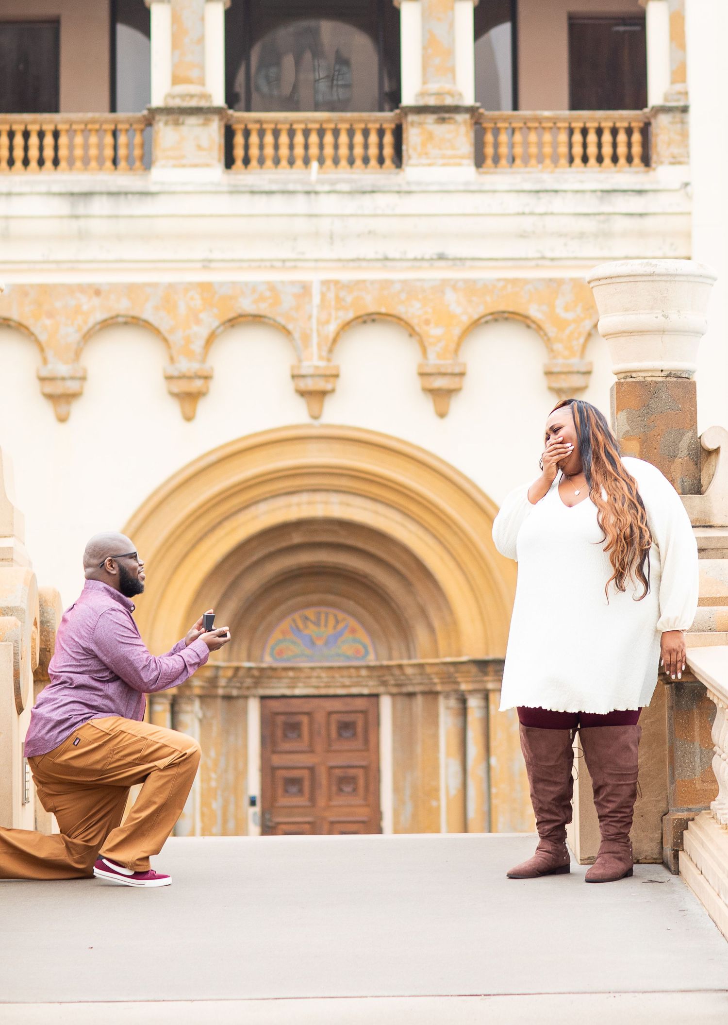 Two people sharing a special moment on steps of an ornate building with beautiful archways.