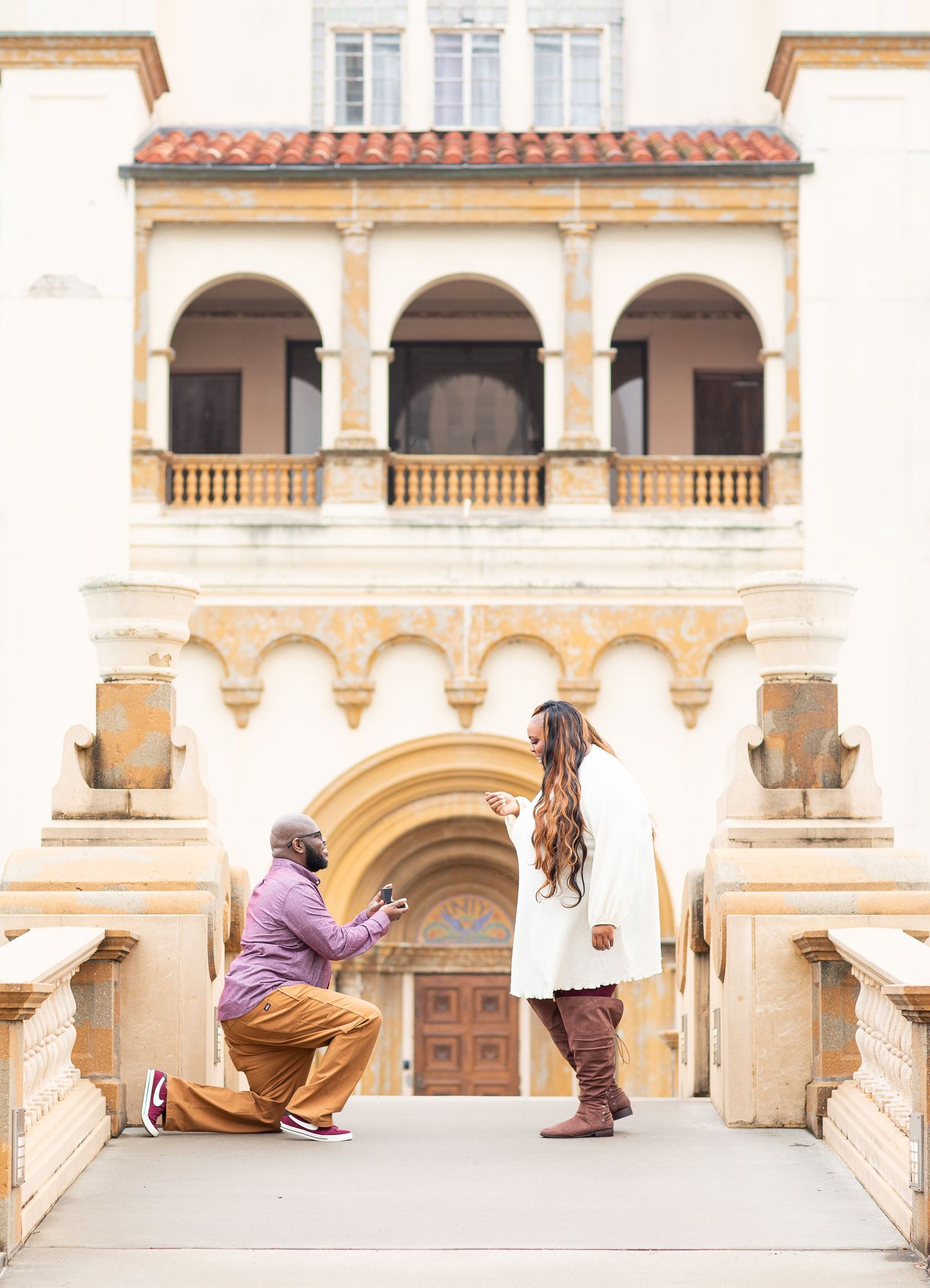 A couple's engagement captured against the backdrop of a Spanish colonial style building.