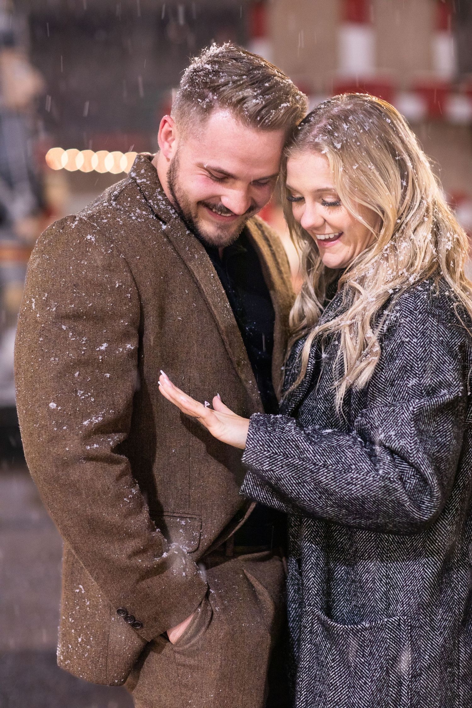 Couple shares intimate moment while snow falls at winter carnival.