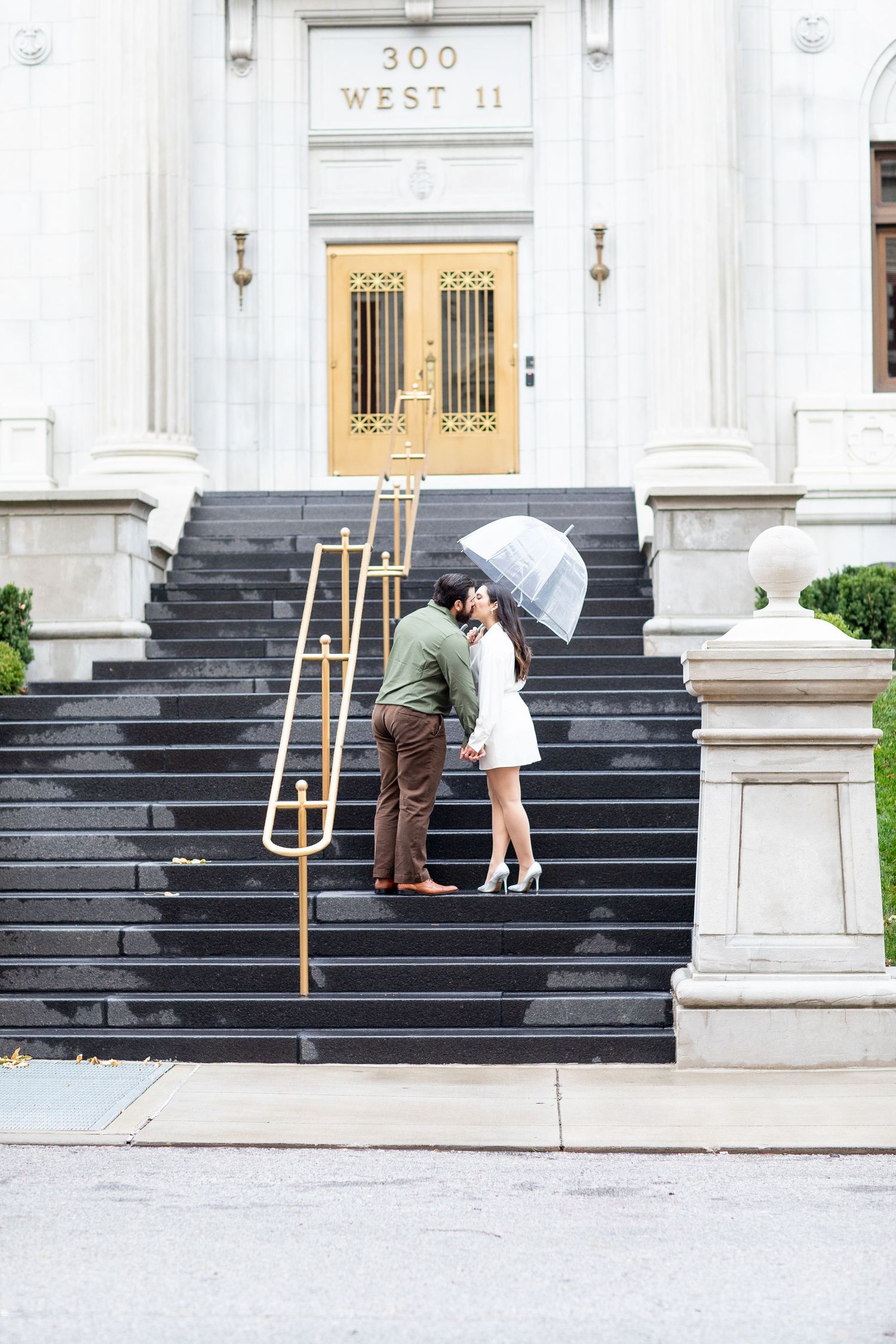 Couple sharing a moment under an umbrella on elegant stone steps at 300 West 11.