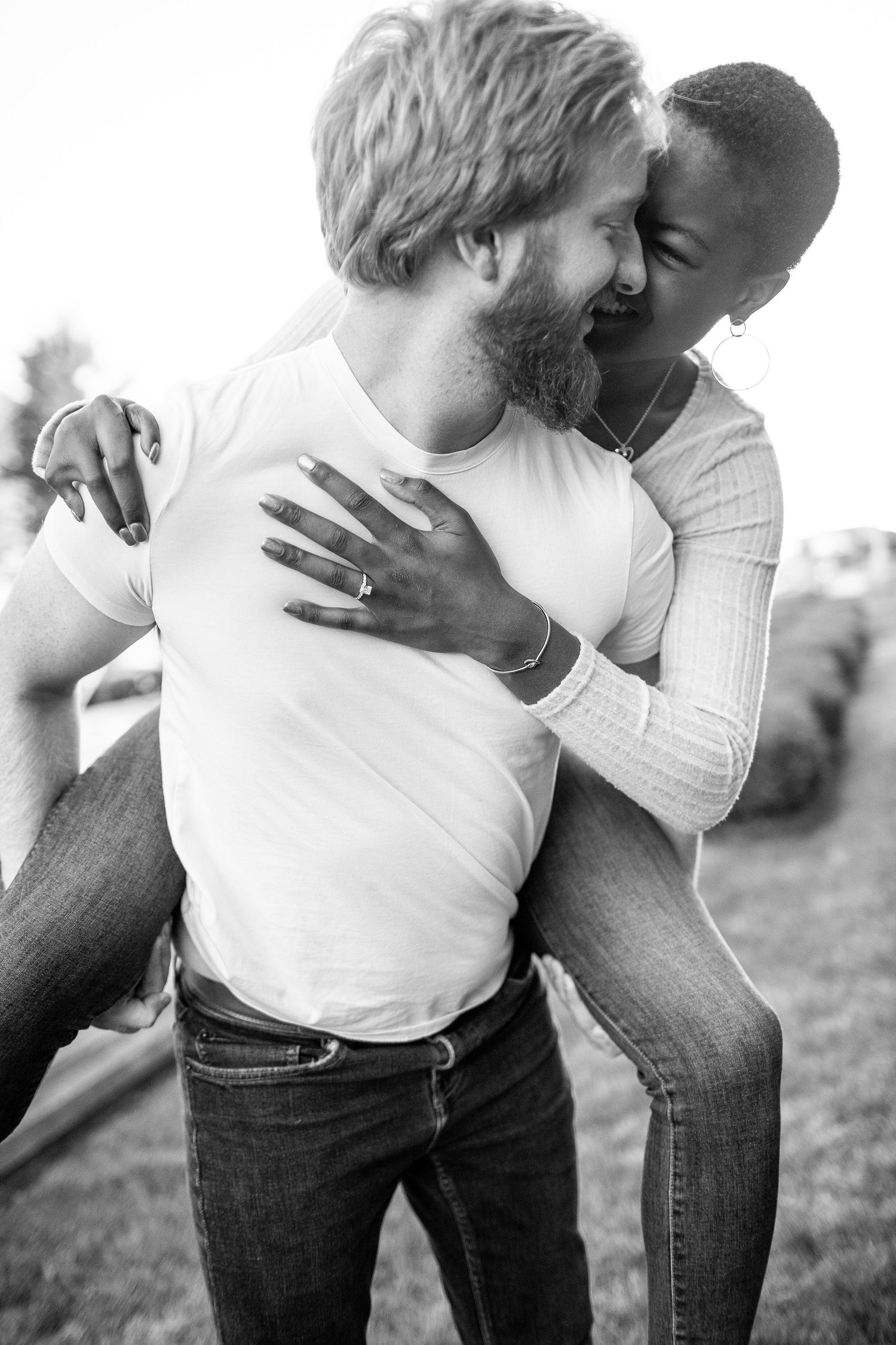 Romantic black and white candid moment of couple embracing outdoors.