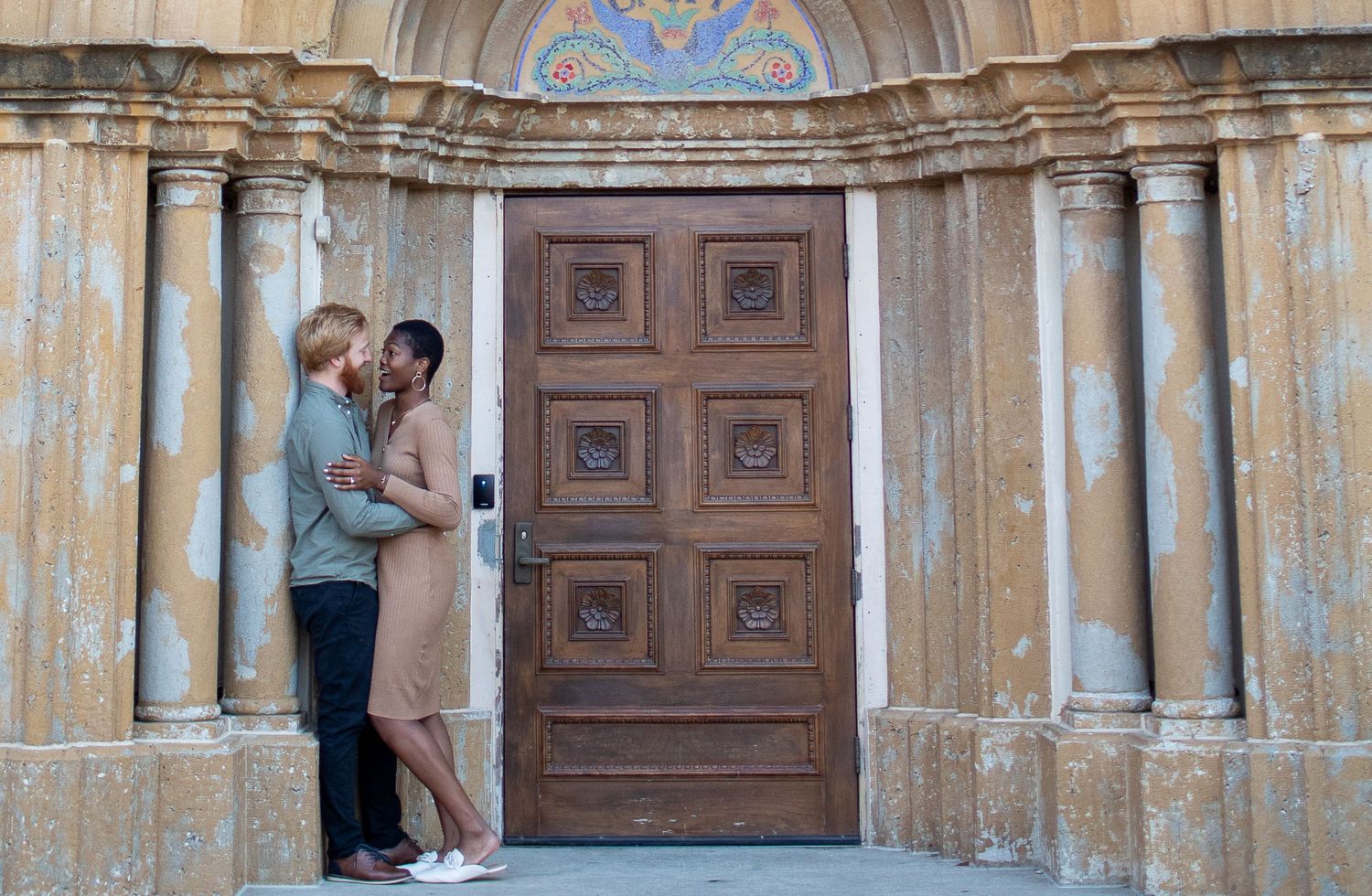 Couple sharing romantic moment in ornate stone doorway with classical architecture.