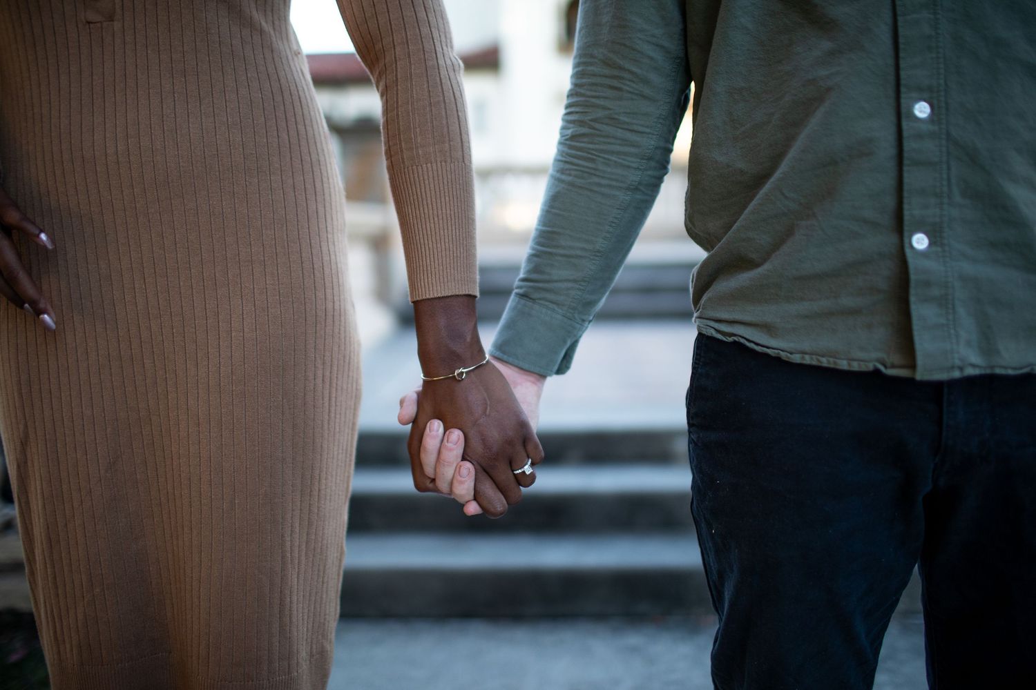 Close-up shot of couple holding hands while walking down stone steps.
