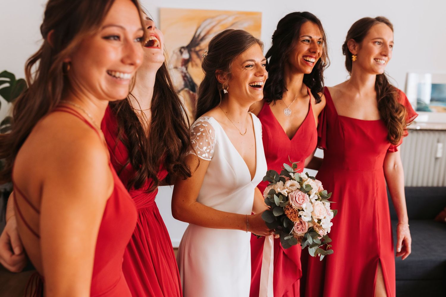 A group celebrating at a wedding wearing red and white dresses with a floral bouquet.