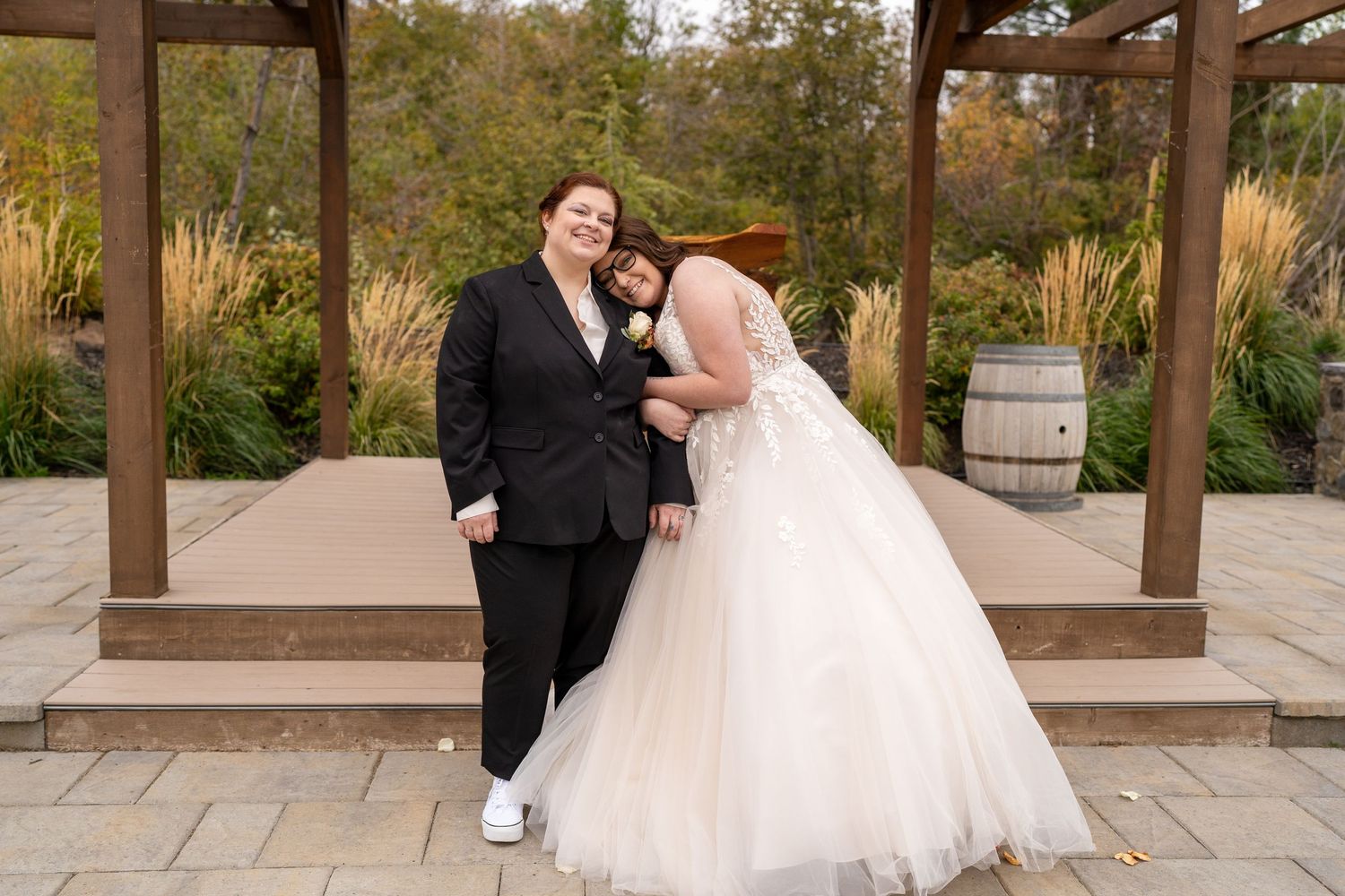 Candid moment between wedding couple under wooden pergola in garden setting.
