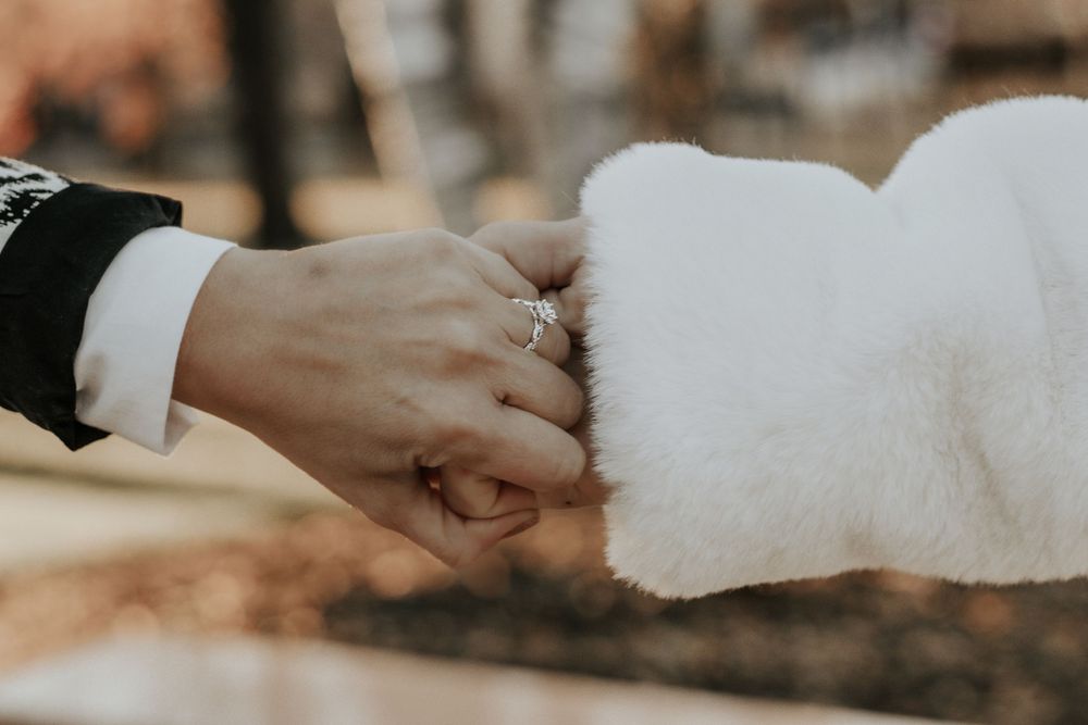 Close-up shot of hands touching while wearing a white fluffy coat.