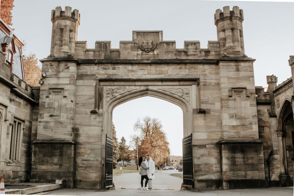 A distant view of figures walking through a grand stone castle archway.