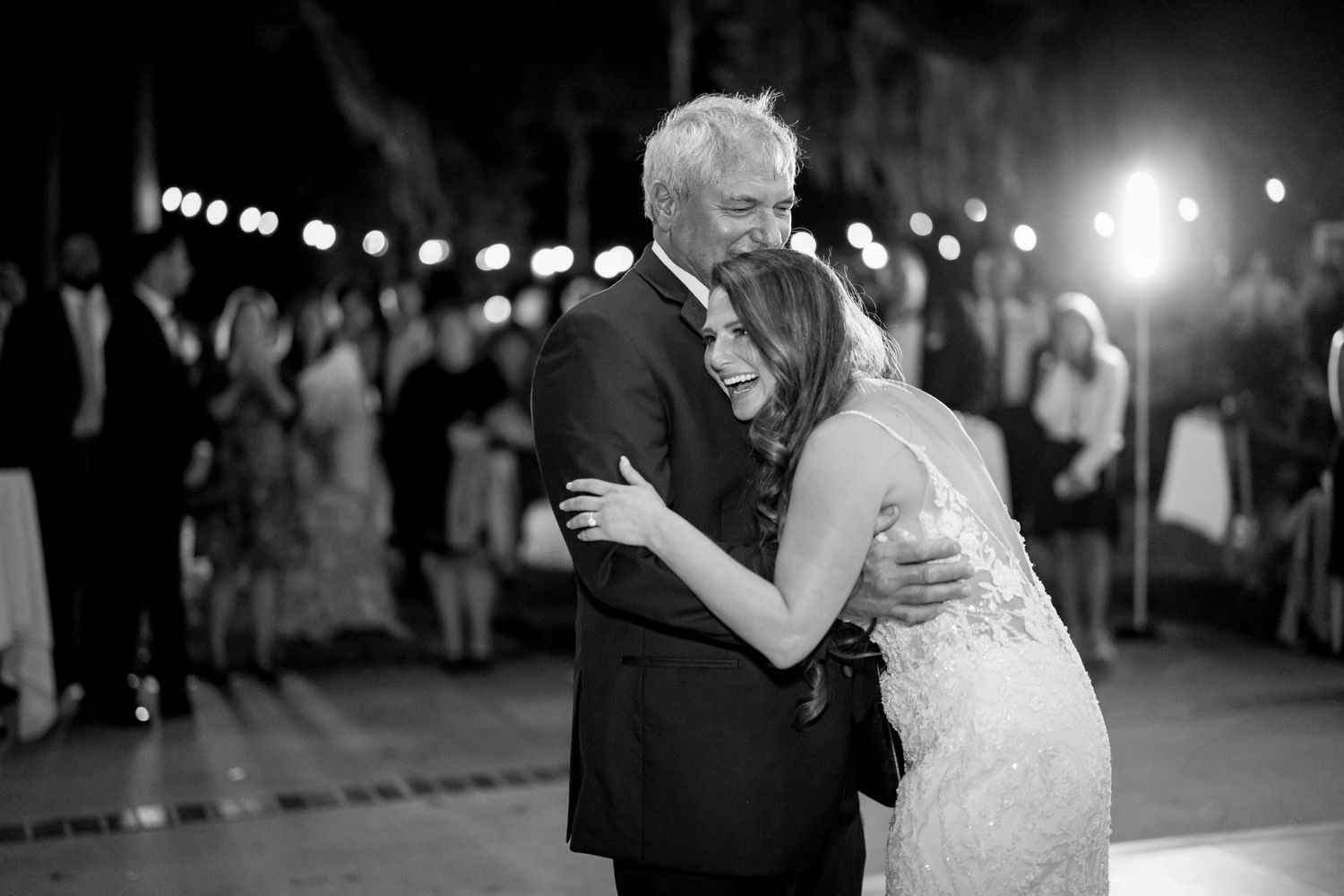 A tender black and white moment captured during a wedding dance under string lights.