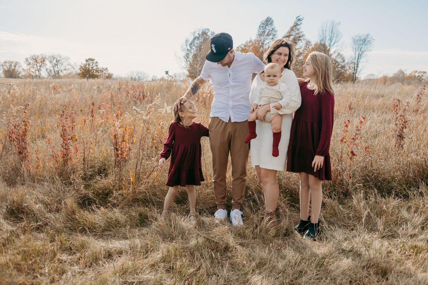 Family shares a joyful moment together in a rustic autumn field setting.