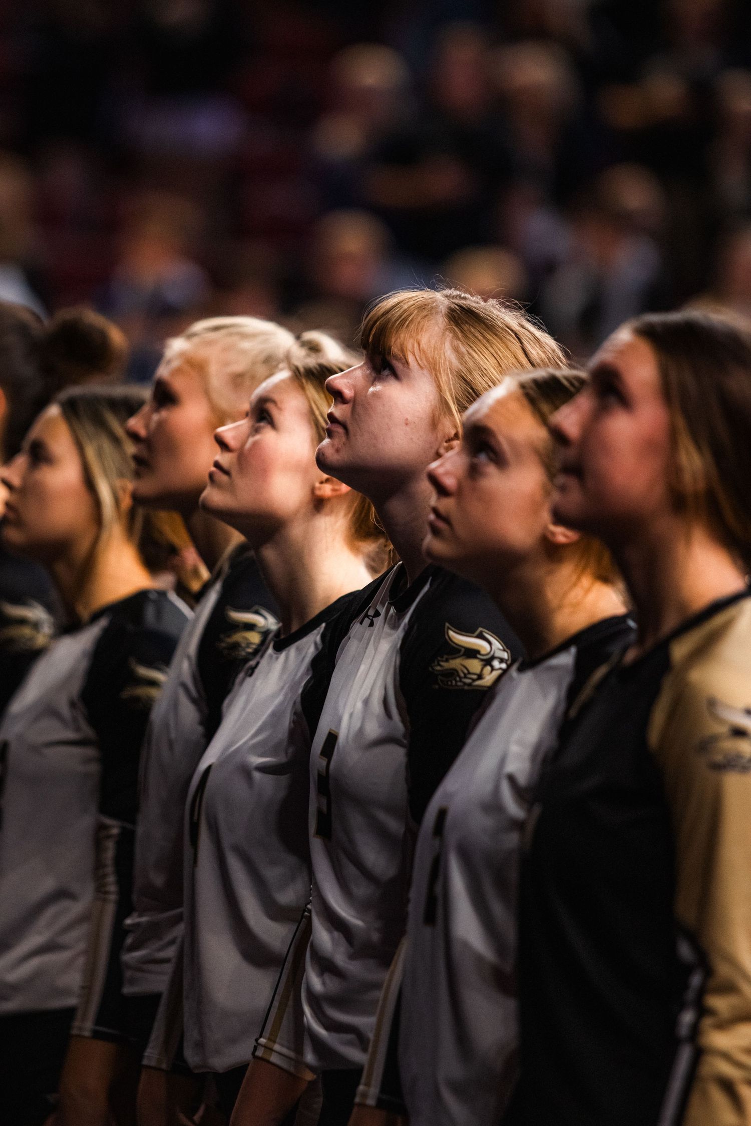 Row of choir members in matching grey outfits looking upward during performance.