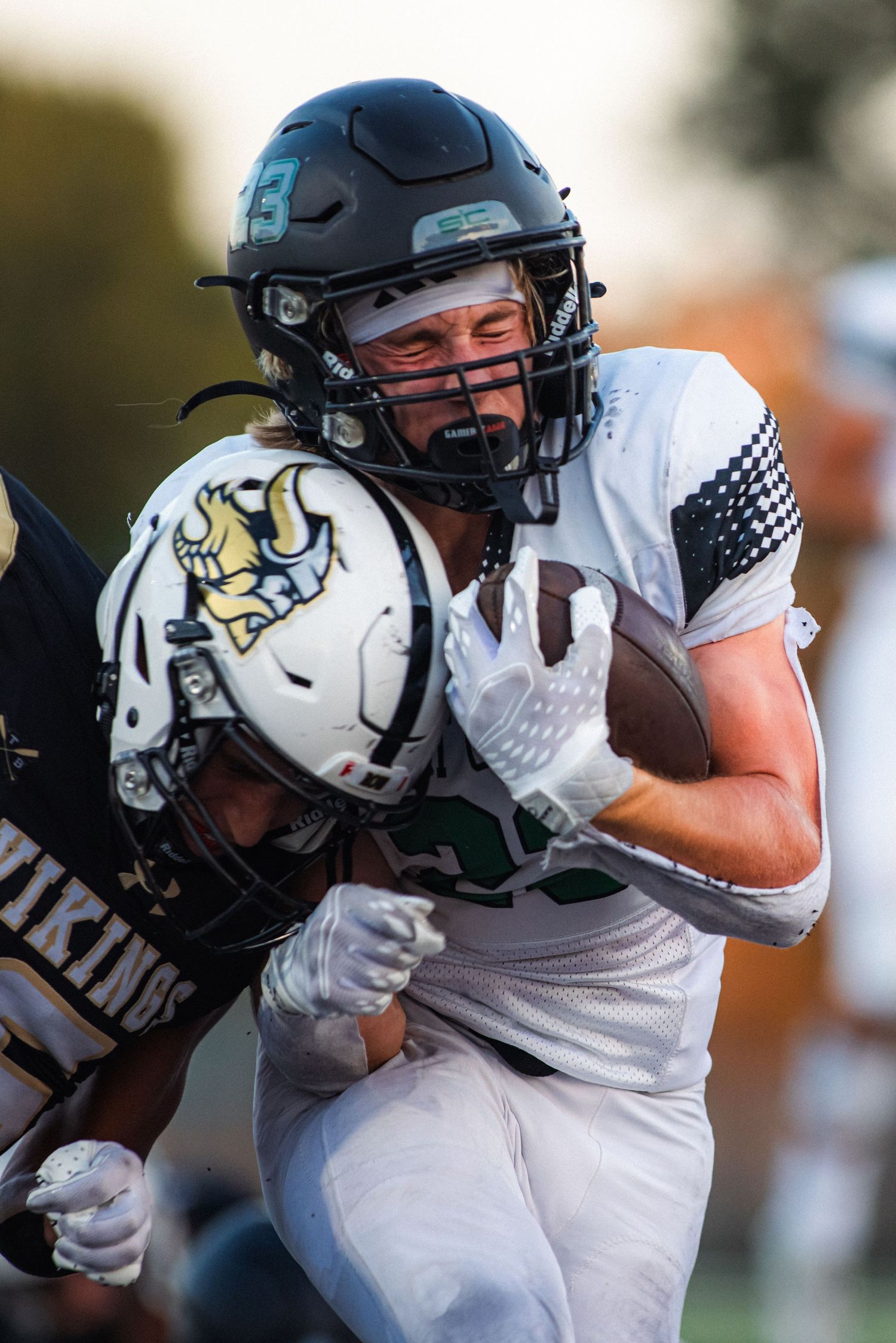 Football player in white uniform carrying ball while running during game action.