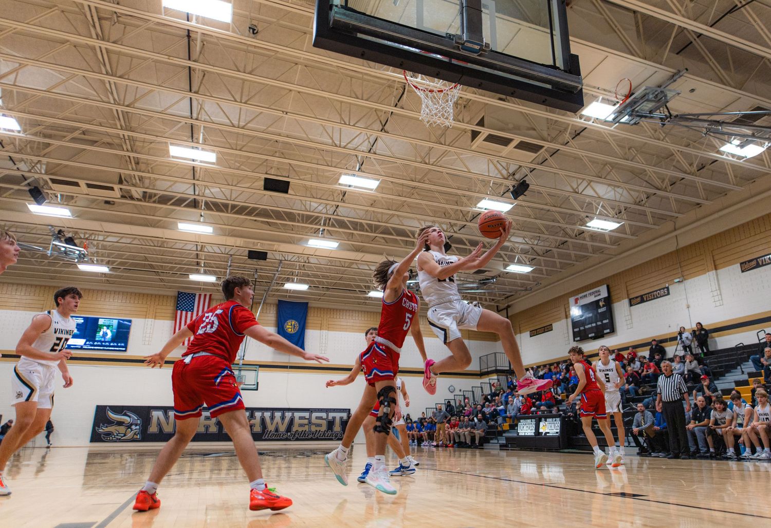 High school basketball players jump for a rebound during an intense game.