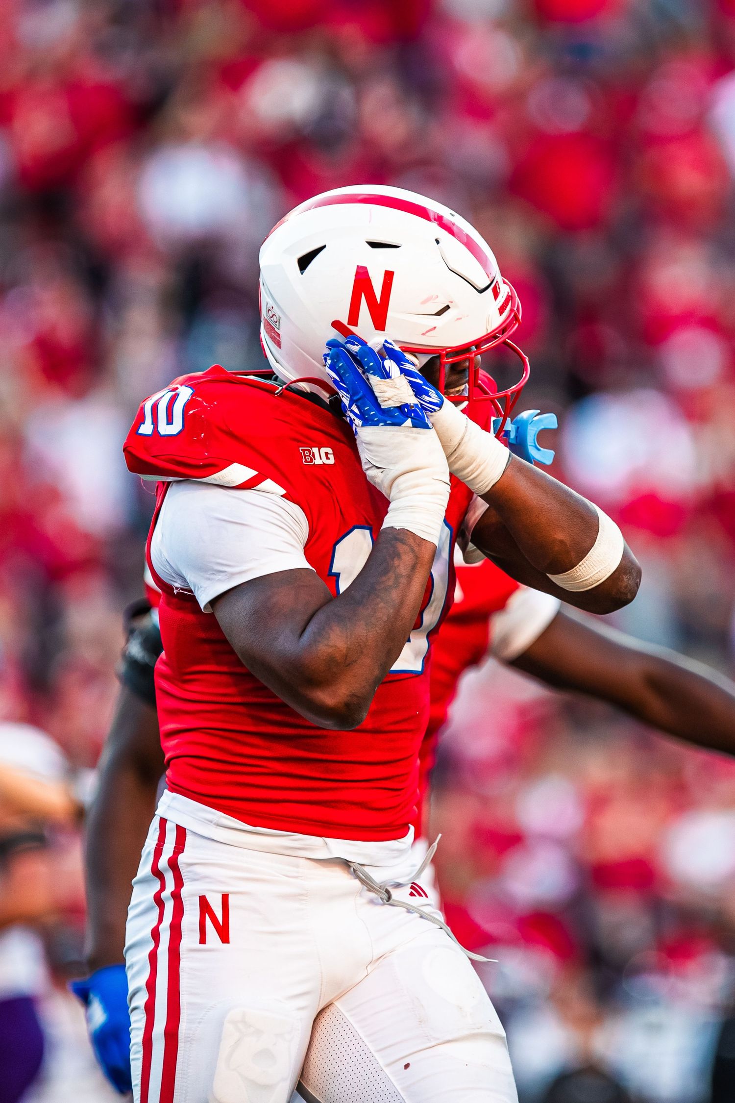 Nebraska football player in red uniform celebrates during game with animated gesture.