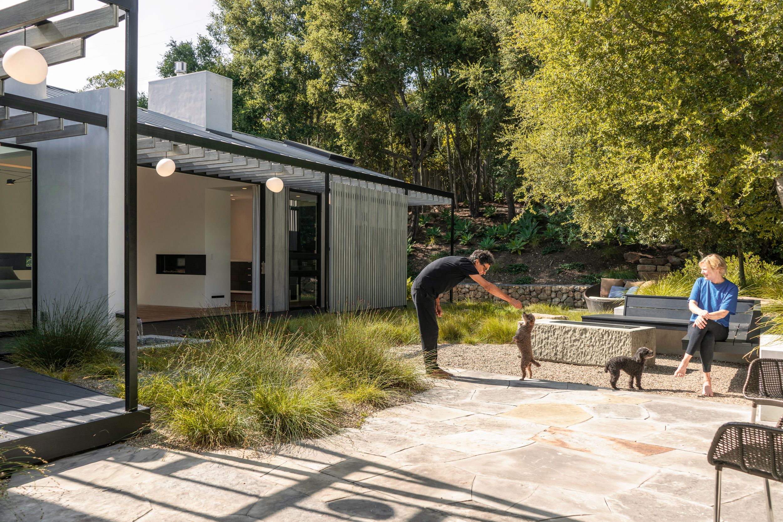 Modern home exterior with patio seating area and native landscaping in a natural setting.