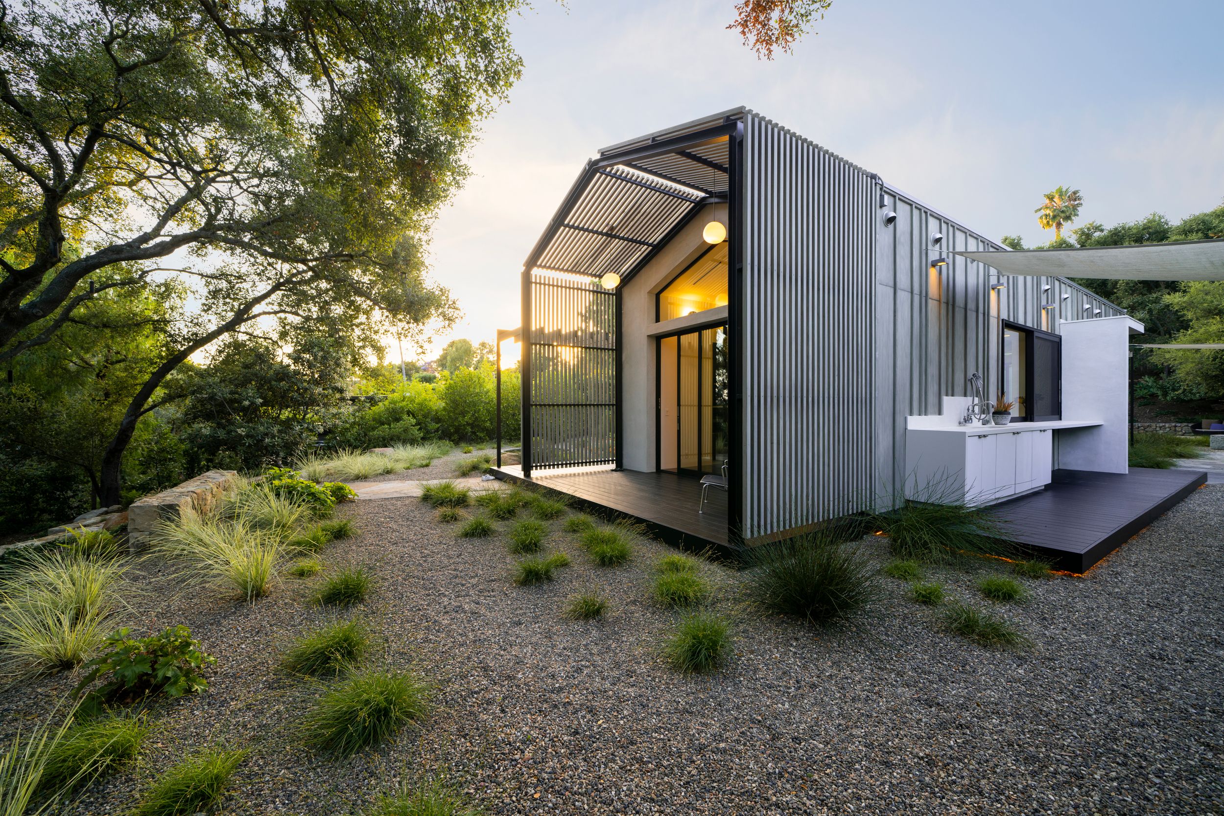 Contemporary gray modular home with large windows and angular architecture set in a natural landscape.
