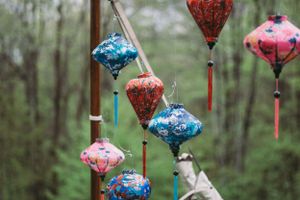 Colorful paper lanterns hanging as wedding decorations against a forest backdrop.