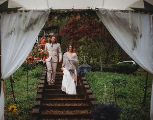 A decorated outdoor wedding venue with white drapes and wooden stairs in a garden setting.