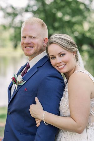 Romantic outdoor wedding portrait against natural greenery background showing formal attire.