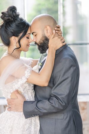 A tender moment shared between newlyweds in formal wedding attire.