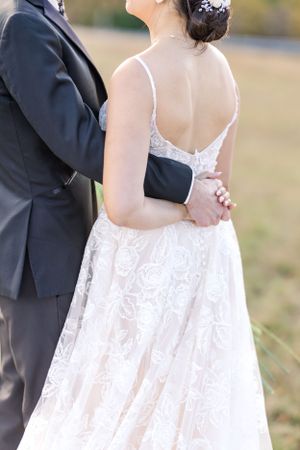 Close-up of wedding couple embracing, showing intricate lace details of the bride's dress.