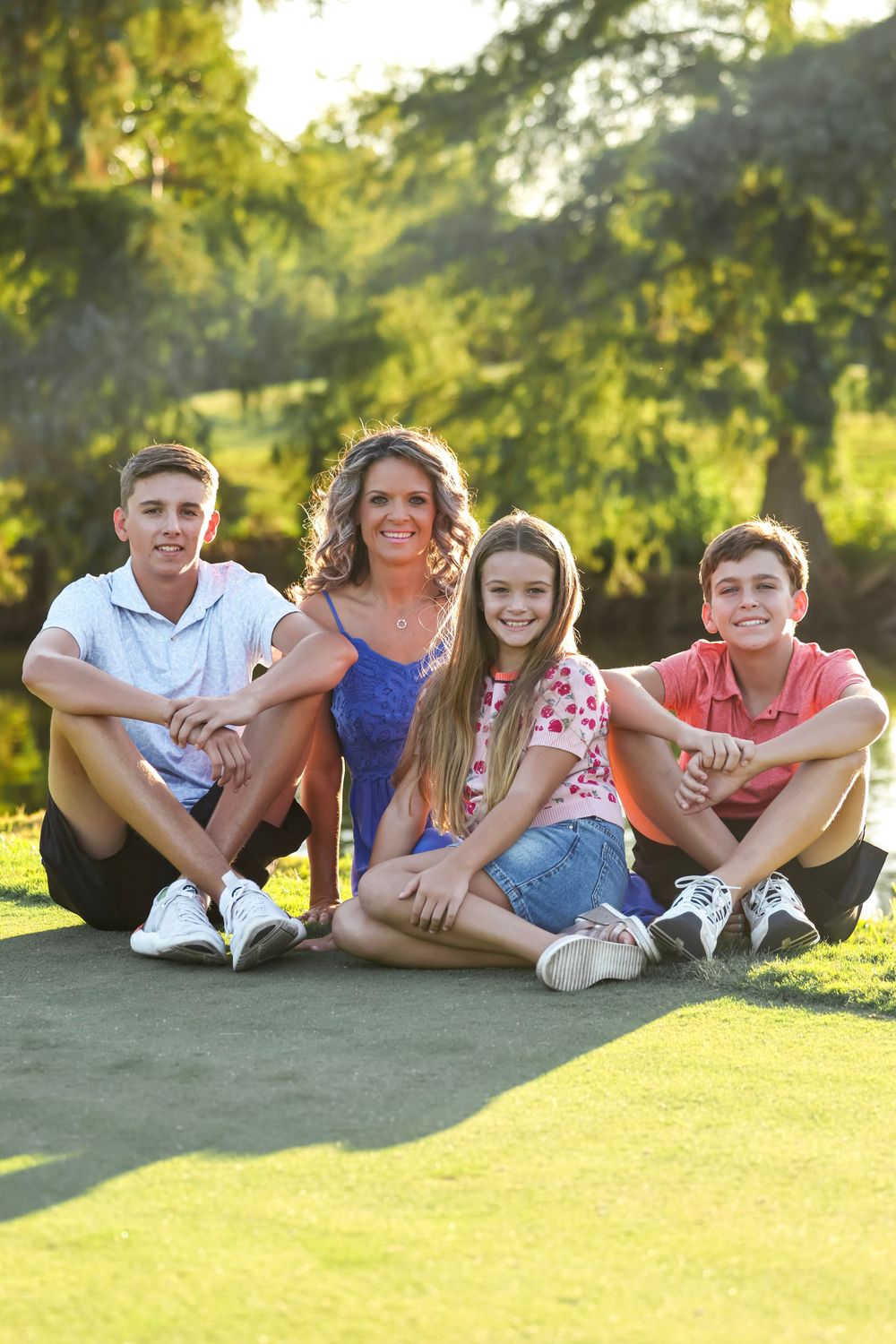 Family members relaxing together on grass during a sunny outdoor photo session.