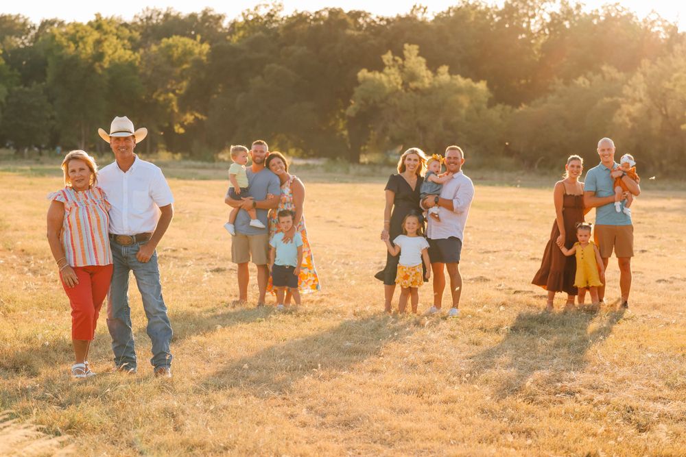 Multiple family groups pose together during sunset in a golden field.