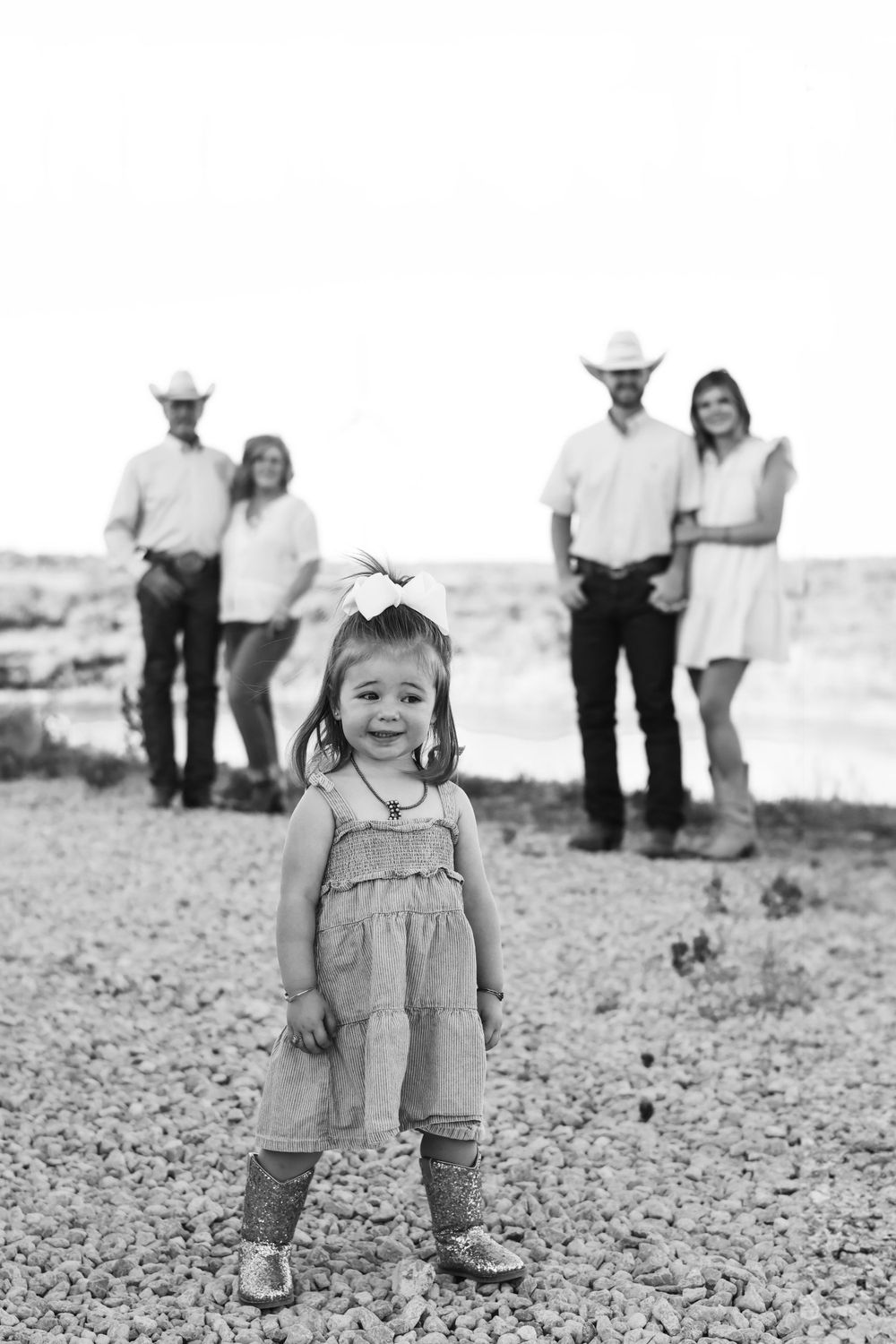 Black and white portrait series of a child playing in rocky terrain with adults in background.