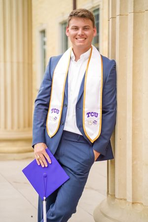 Graduate in TCU honors stole poses confidently against classical columns.