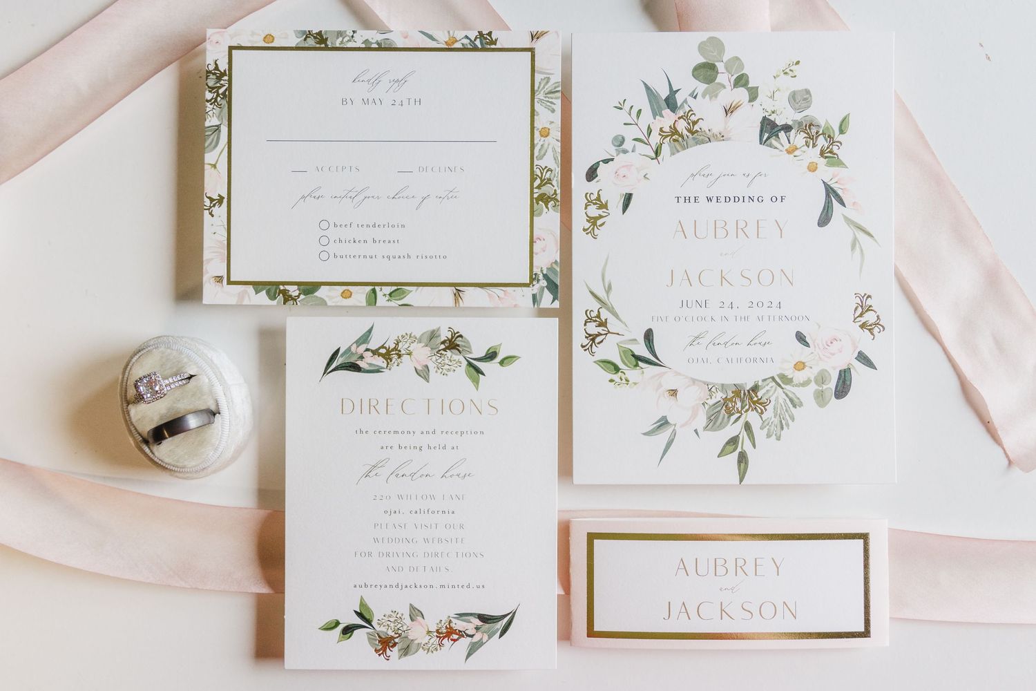 Elegant wedding invitation suite with floral design and pink ribbon accents.