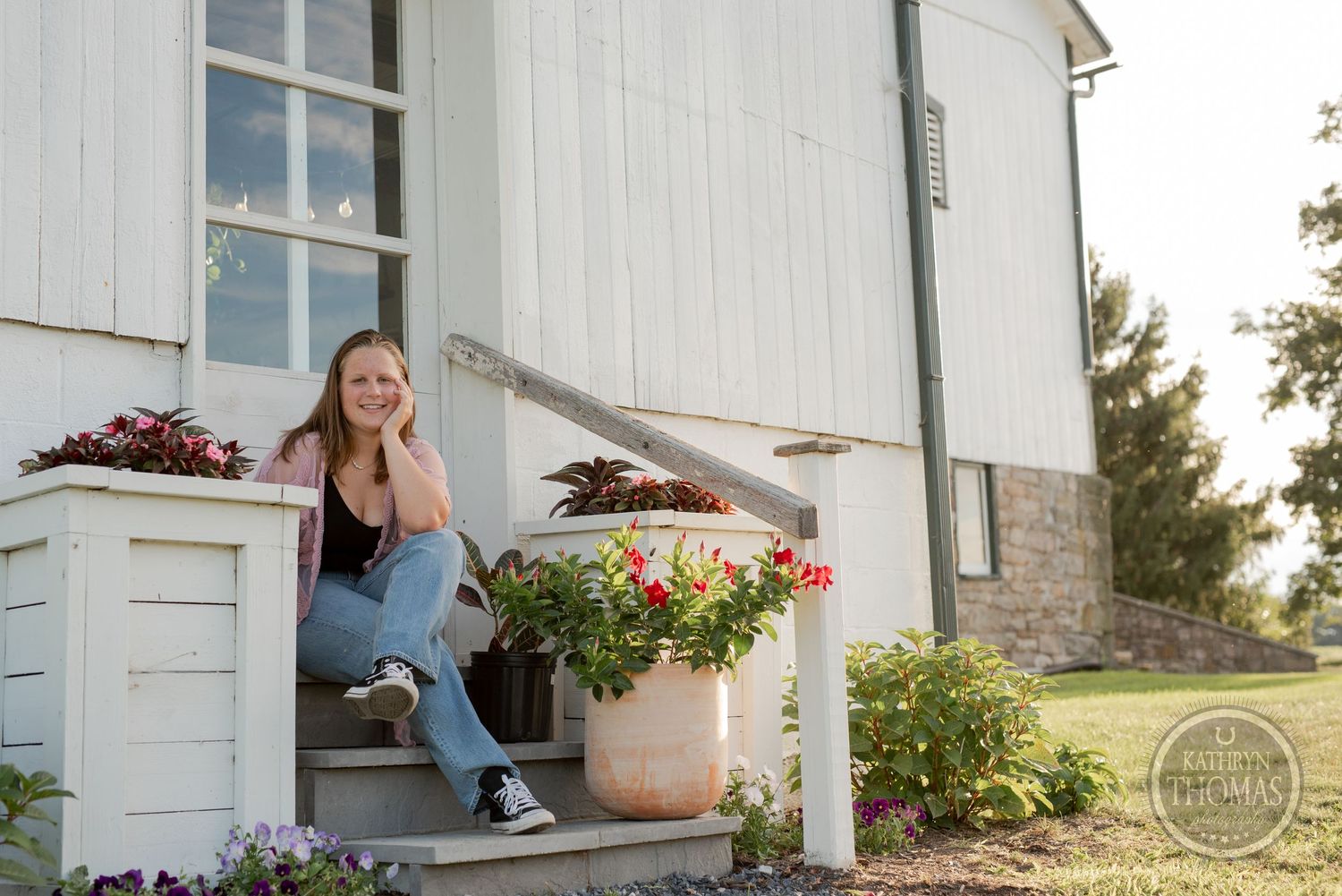 A casual portrait on white farmhouse steps with potted flowers and greenery.