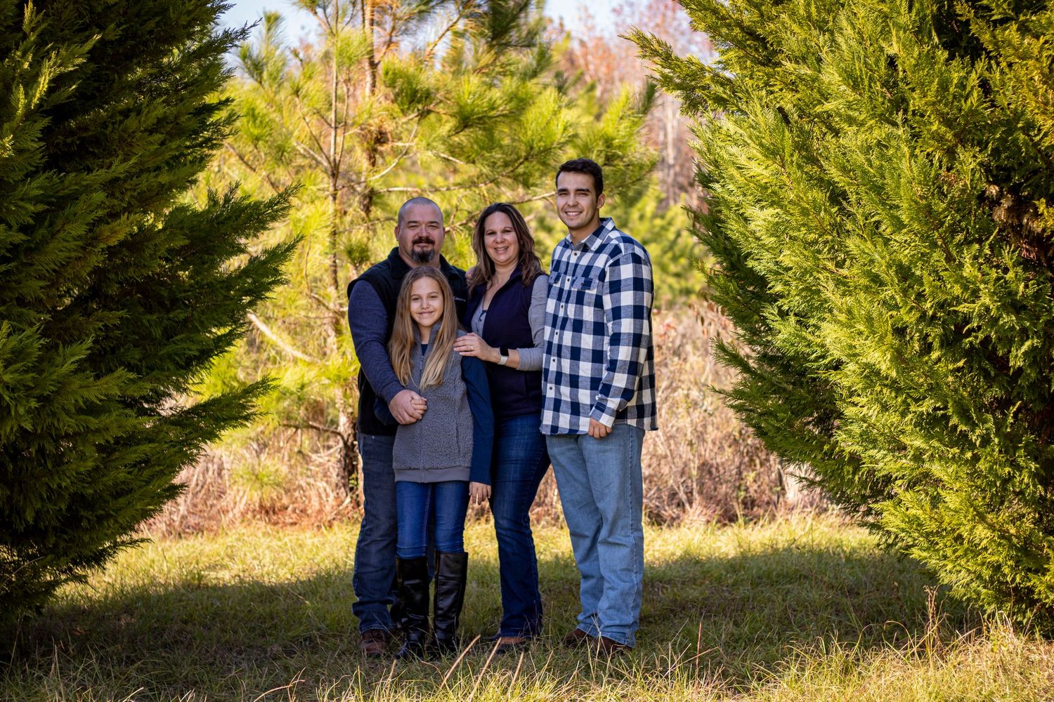 family of four waring navy blue around some trees