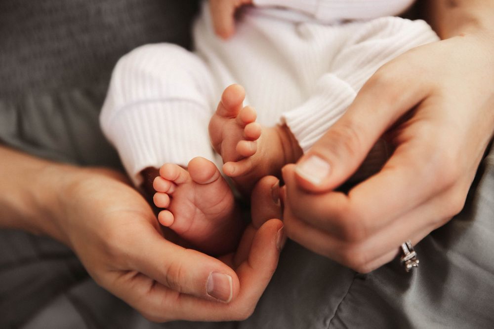 Close-up image of a mother's hands holding her newborn baby's tiny feet