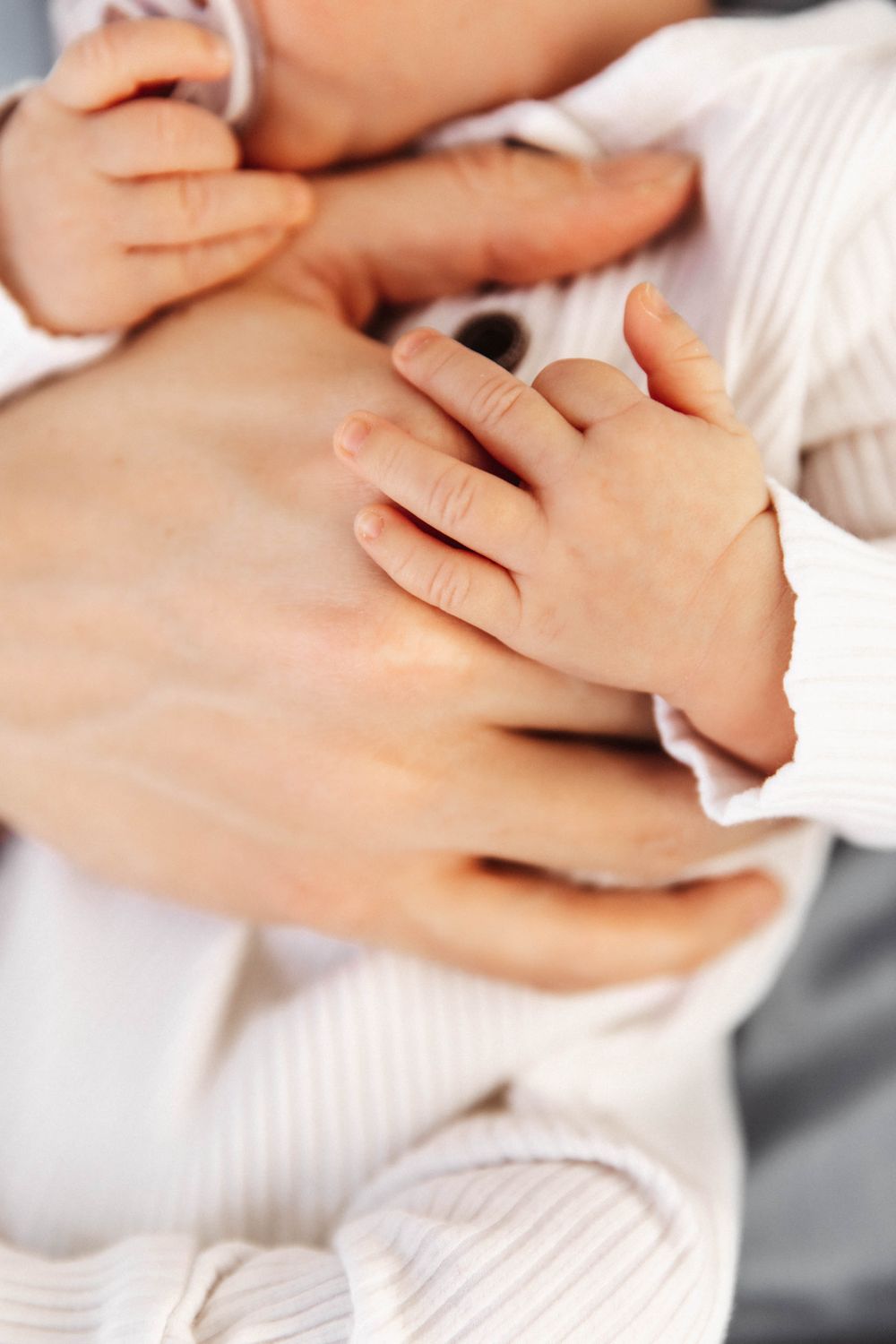 Close-up image of a newborn baby's tiny hands holding onto the hand of his father