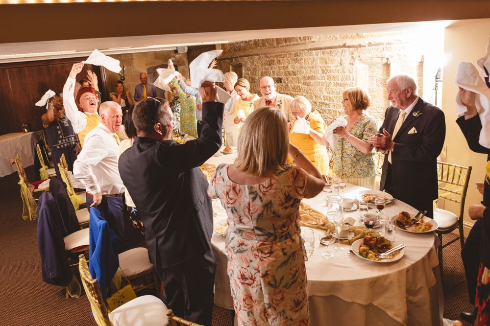 Wedding reception guests mingle and socialize around decorated tables with food and drinks.