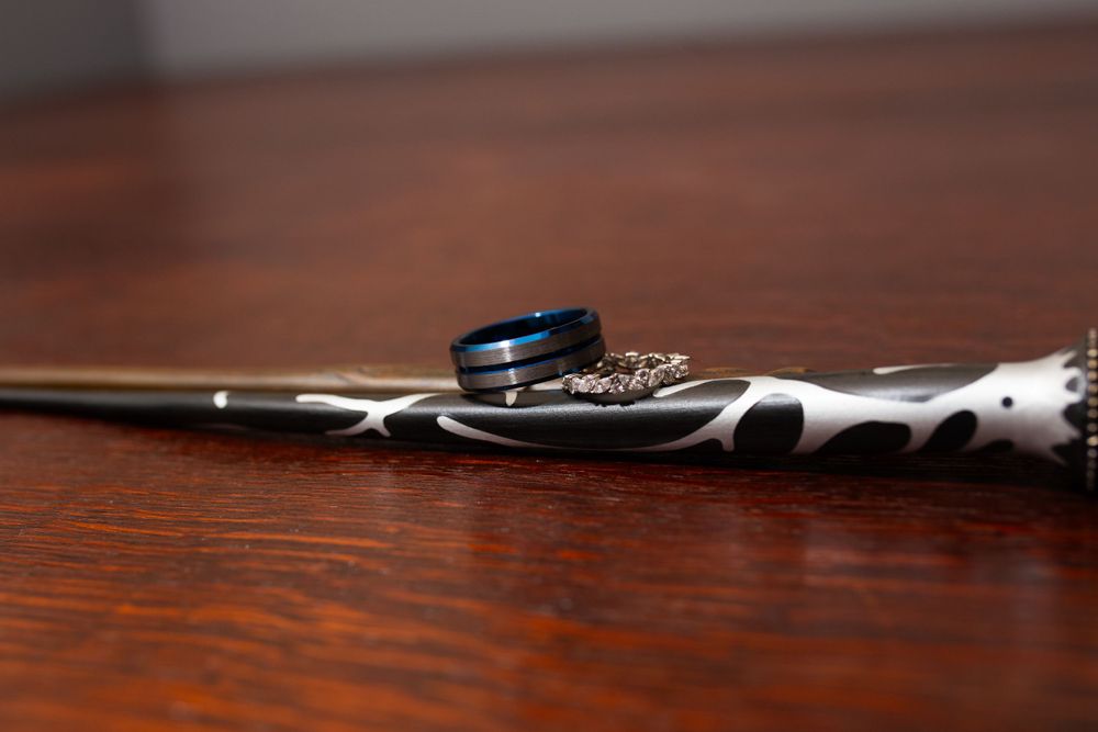 Wedding rings resting on dark wooden surface with dramatic lighting.