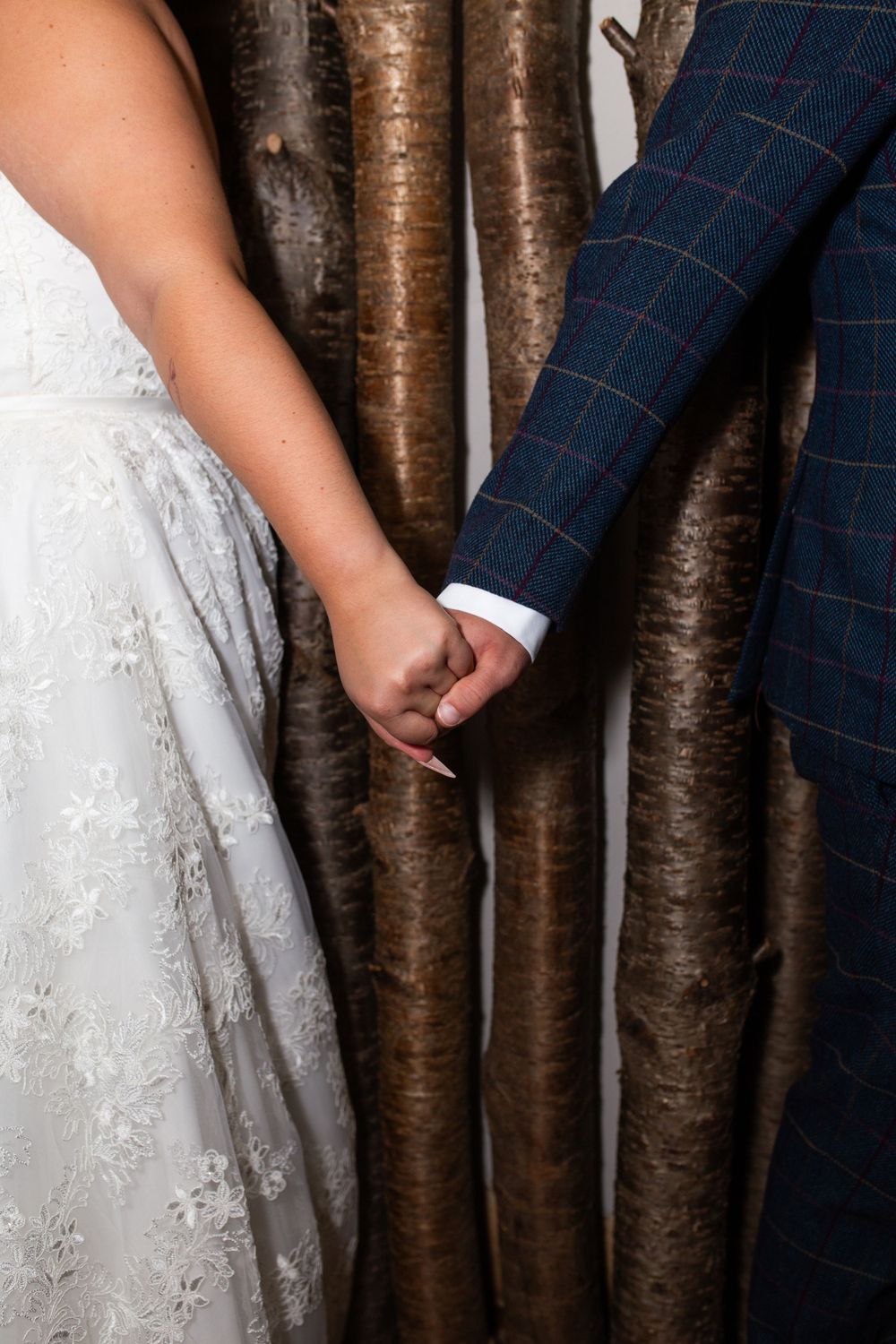 Close-up detail of wedding dress lace against rustic wooden backdrop.