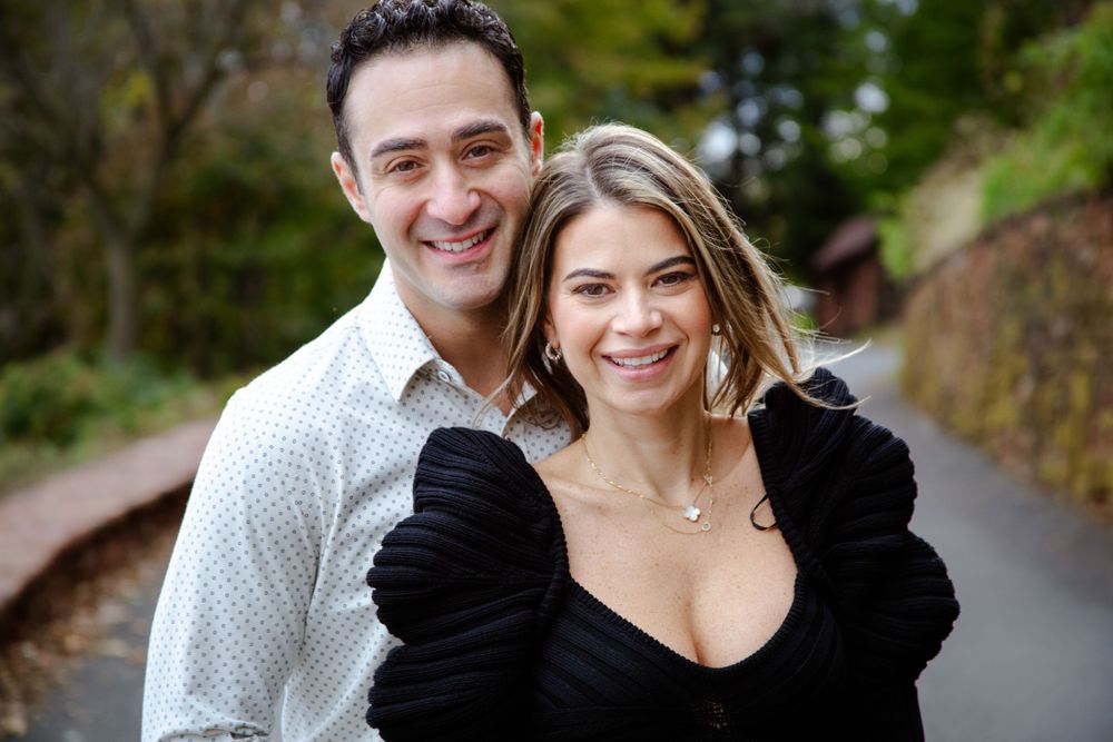 Couple walking together on an autumn path surrounded by fall foliage.
