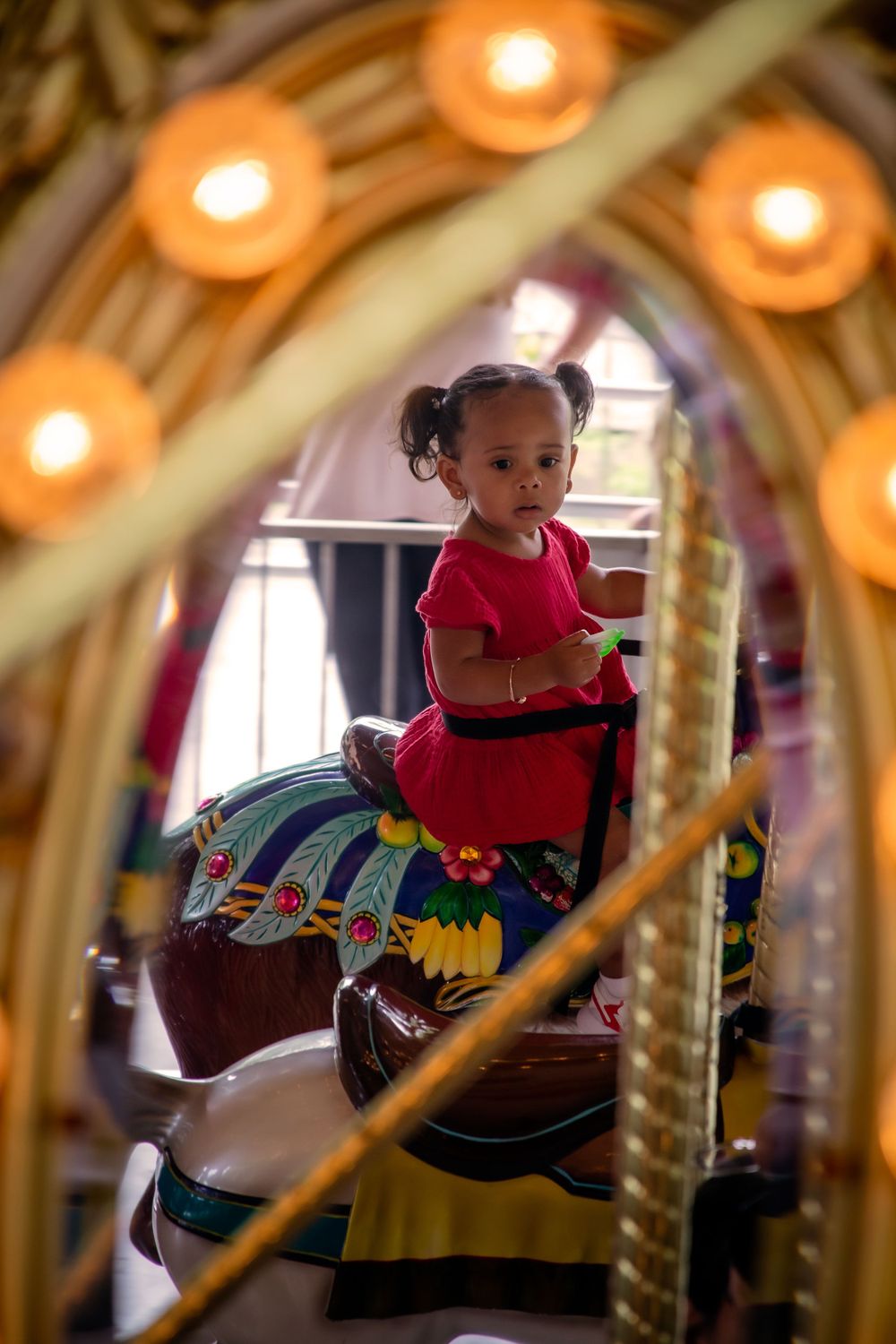 Child riding on a colorful carousel with warm glowing lights overhead.