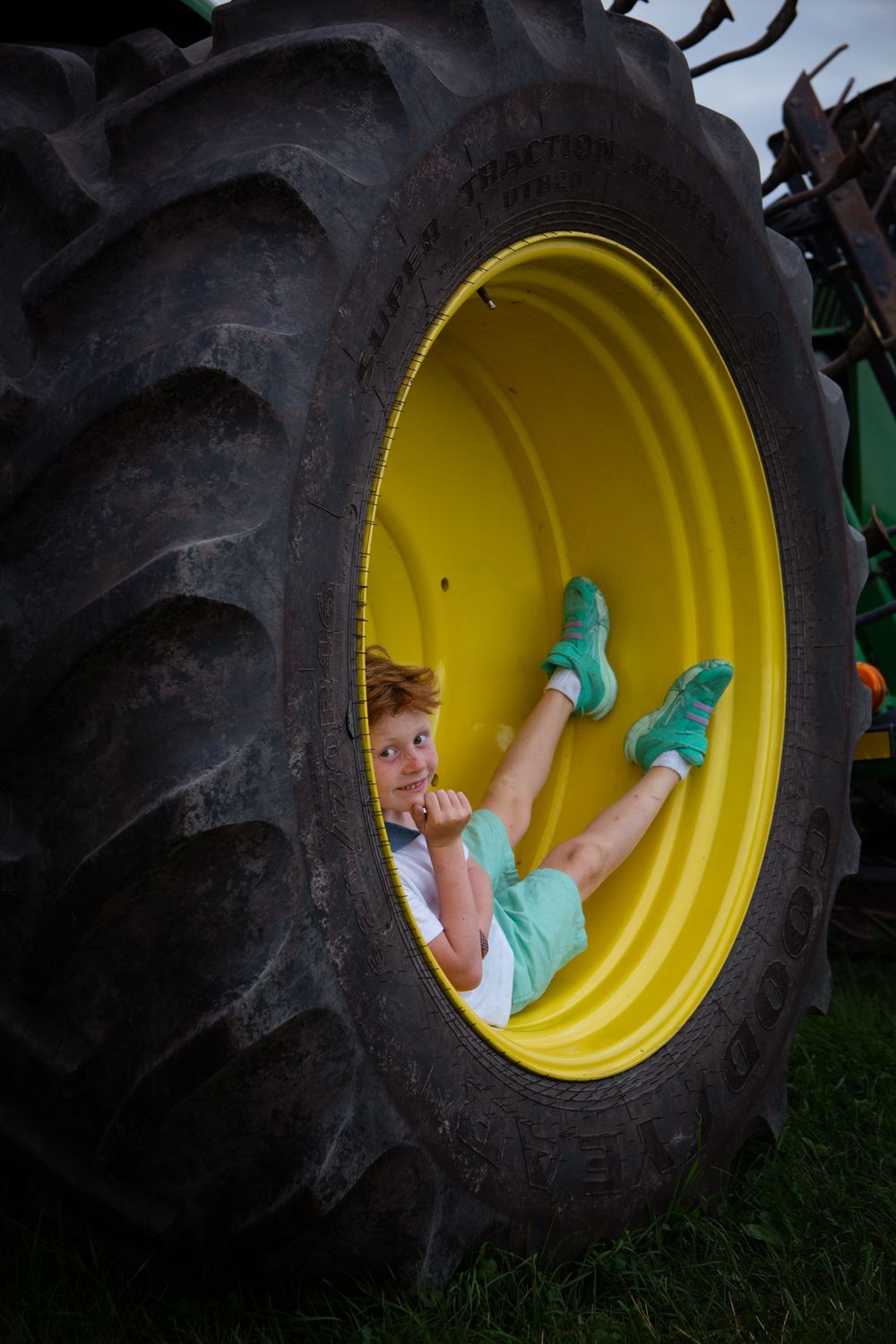Child playing inside a large yellow tractor tire rim in a creative photo sequence.
