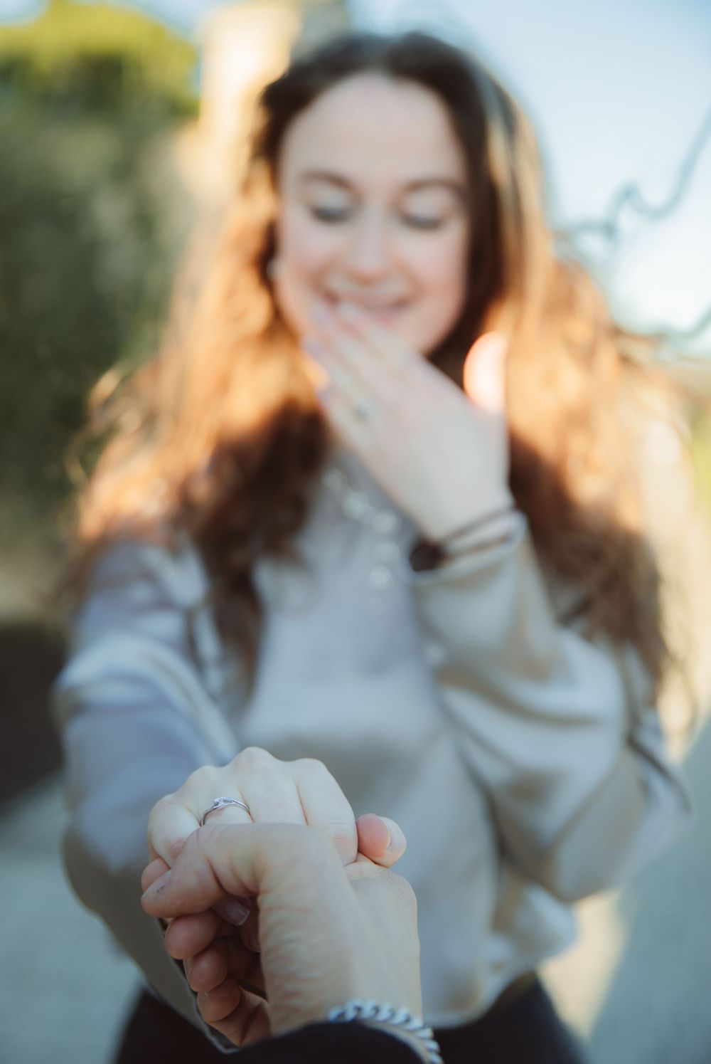 Person in a gray sweater showing emotion in natural outdoor lighting.