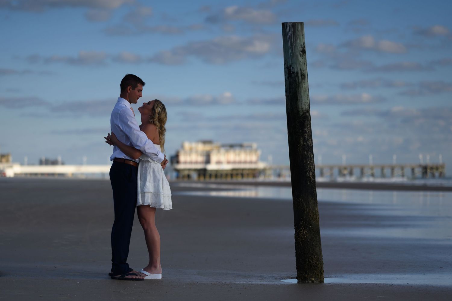 Bride and Groom stand with pier in the background.