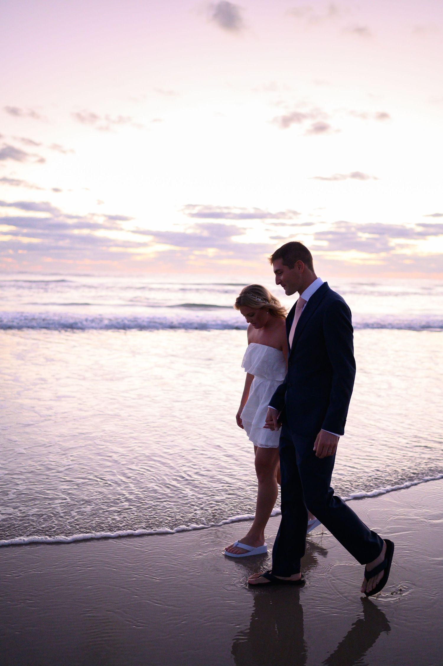 Bride and Groom walking in the surf.