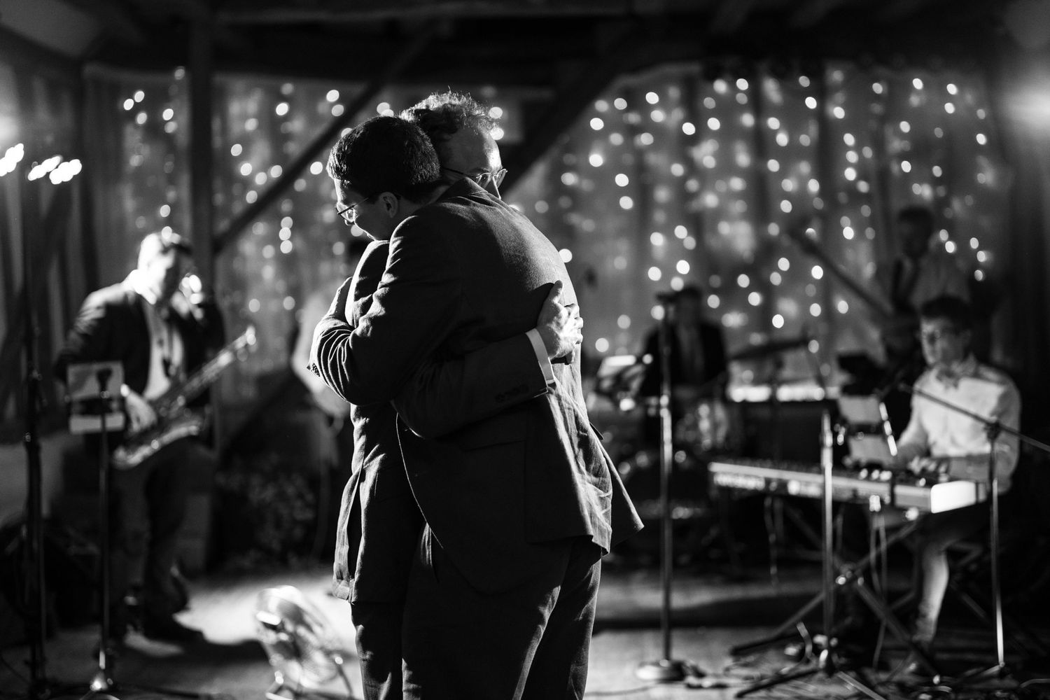 Black and white photo of a musical performance with silhouettes against a backdrop of twinkling lights.