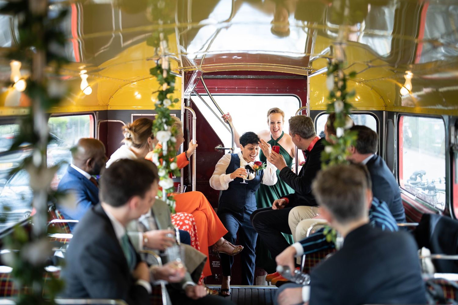 Celebratory gathering inside a decorated vintage bus with guests raising their glasses.