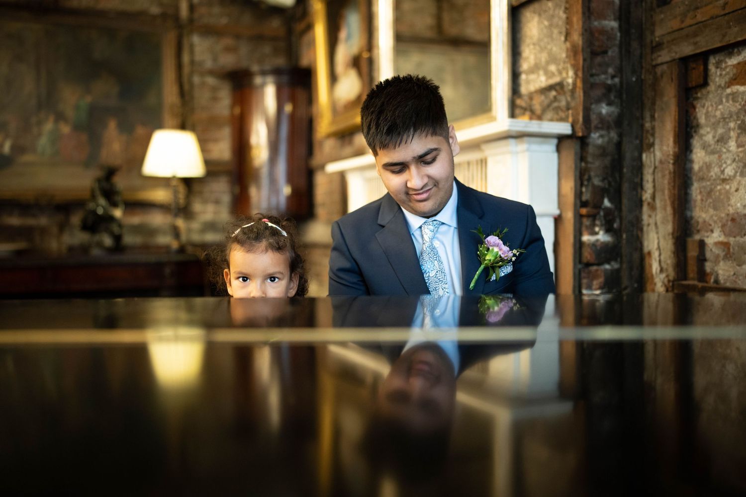 Quiet reflective moment captured at polished piano surface in dimly lit room.