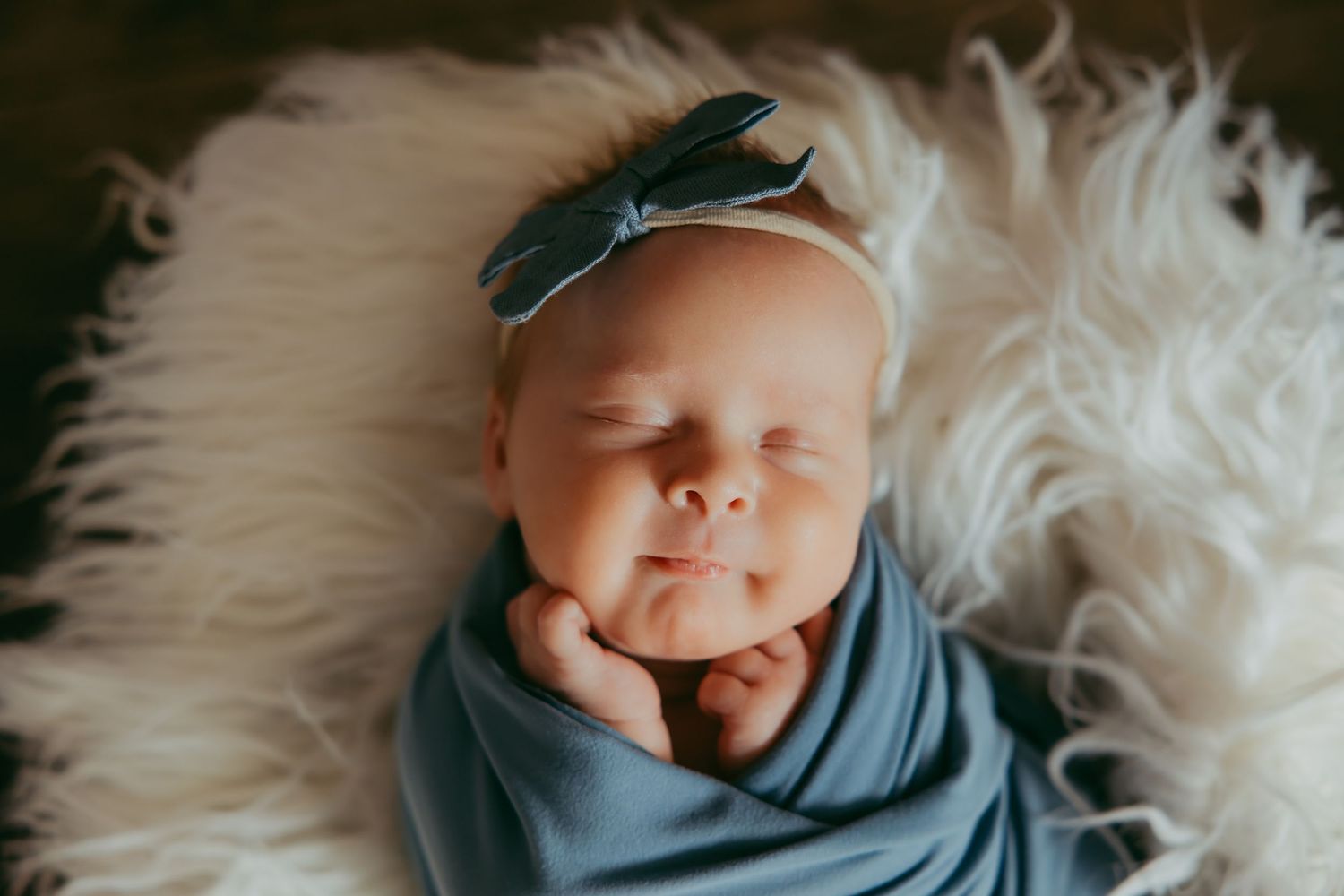Peaceful sleeping newborn wrapped in soft white blanket.