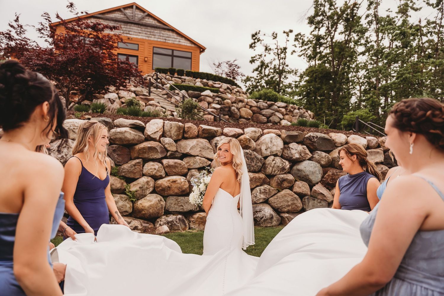 Wedding ceremony group gathered in front of rustic stone wall during intimate outdoor celebration.