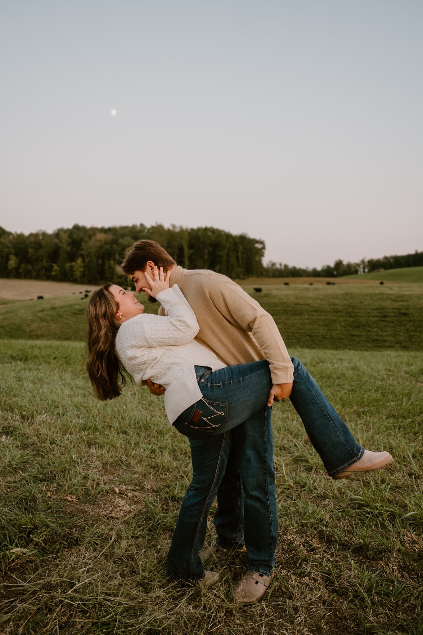 Man dips woman for a kiss in green field at dusk with moon visible in sky High Point NC